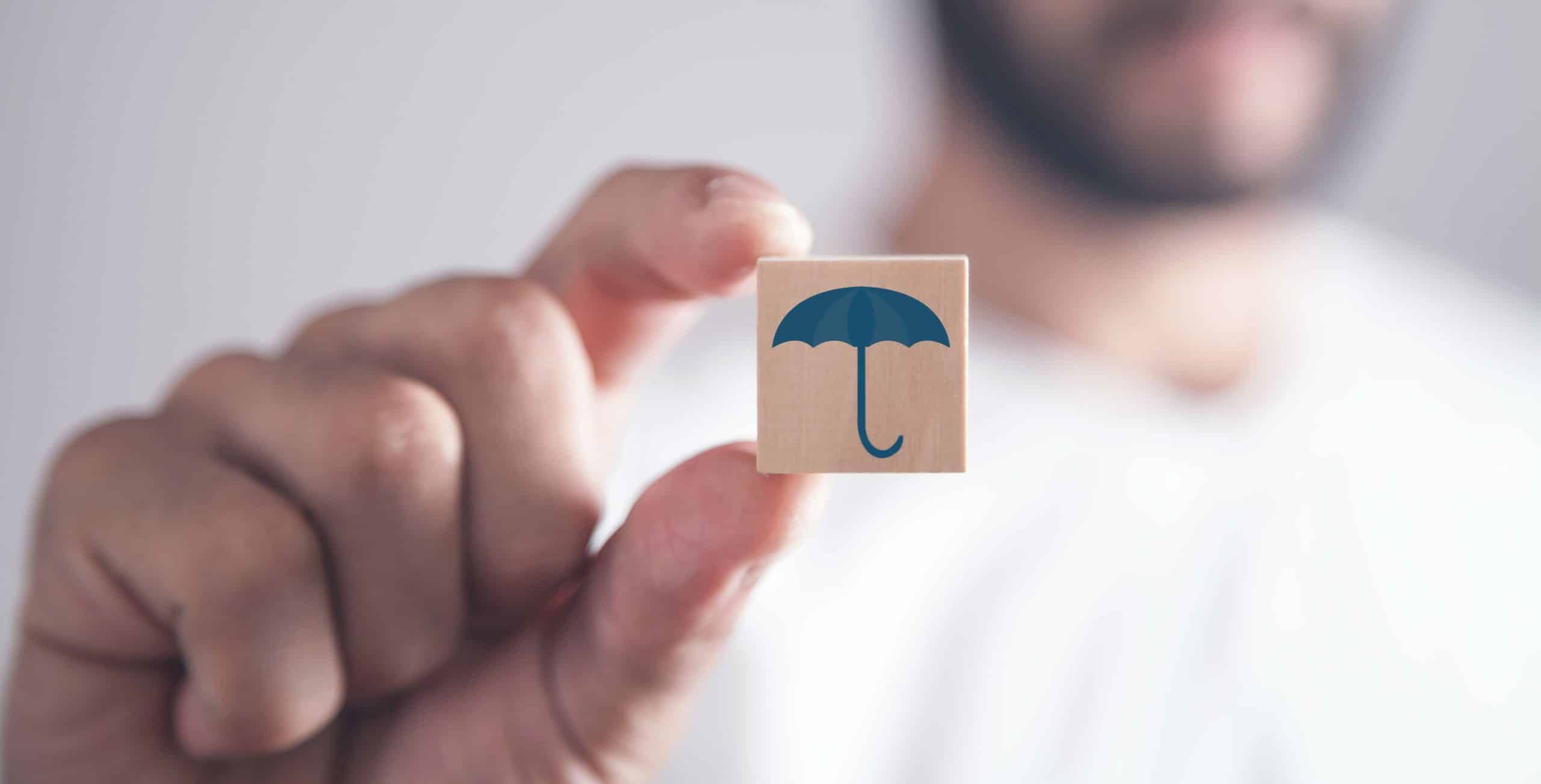 man holding wooden cube with a umbrella symbol.